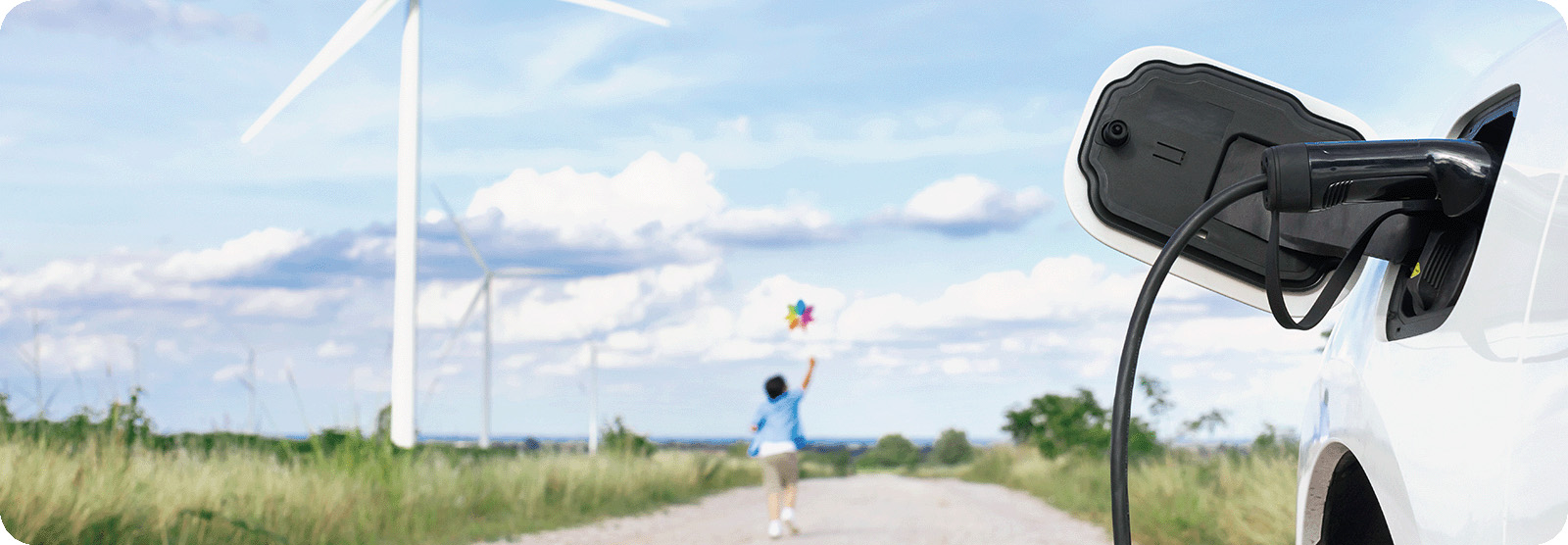 Enfant courant avec un virevent à la main, devant des éoliènnes et un véhicule électrique branché