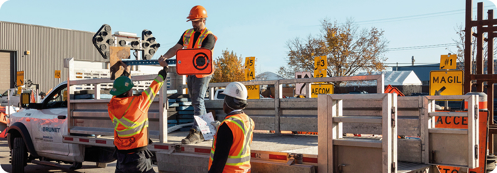 Signaleurs routiers autour d'un camion se passant des panneaux de signalisation à positionner sur la route Association québécoise des transports